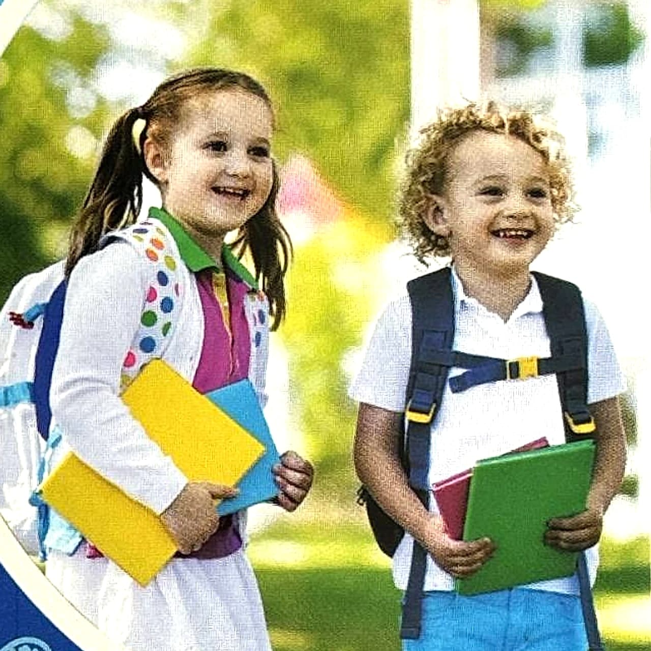 Niña y niño sonriendo con sus mochilas y cuadernos de colores.